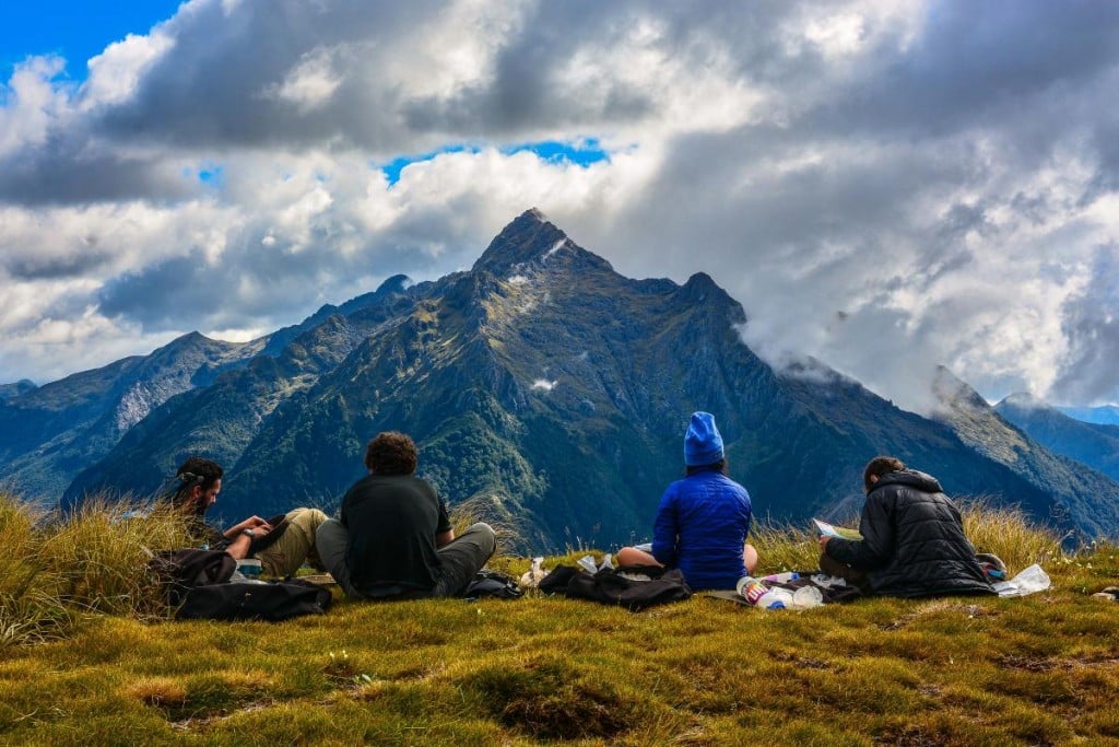 NOLS New Zealand students pause to reflect while sitting in the grass facing the mountains