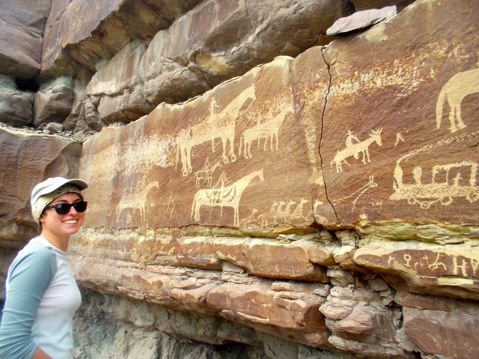 NOLS student poses next to wall with pictographs 