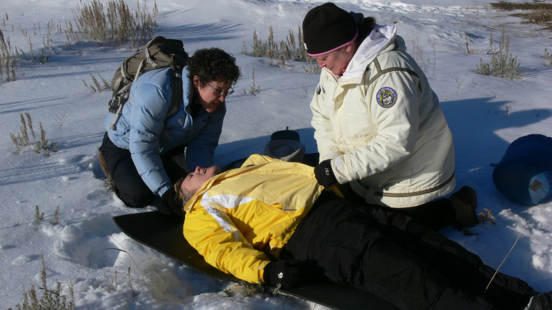 Two wilderness medicine students practice giving patient care during a winter scenario
