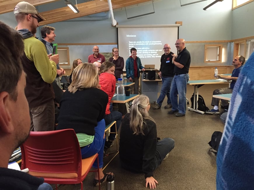 Participants stand and sit in a classroom during a workshop