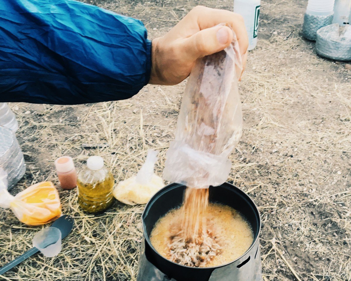 Person pouring dried food into pot