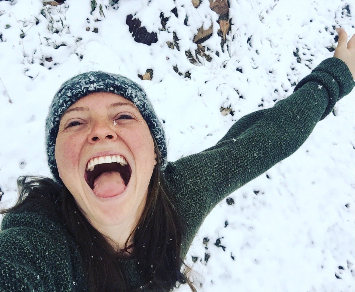 smiling person tries to catch snowflakes on her tongue