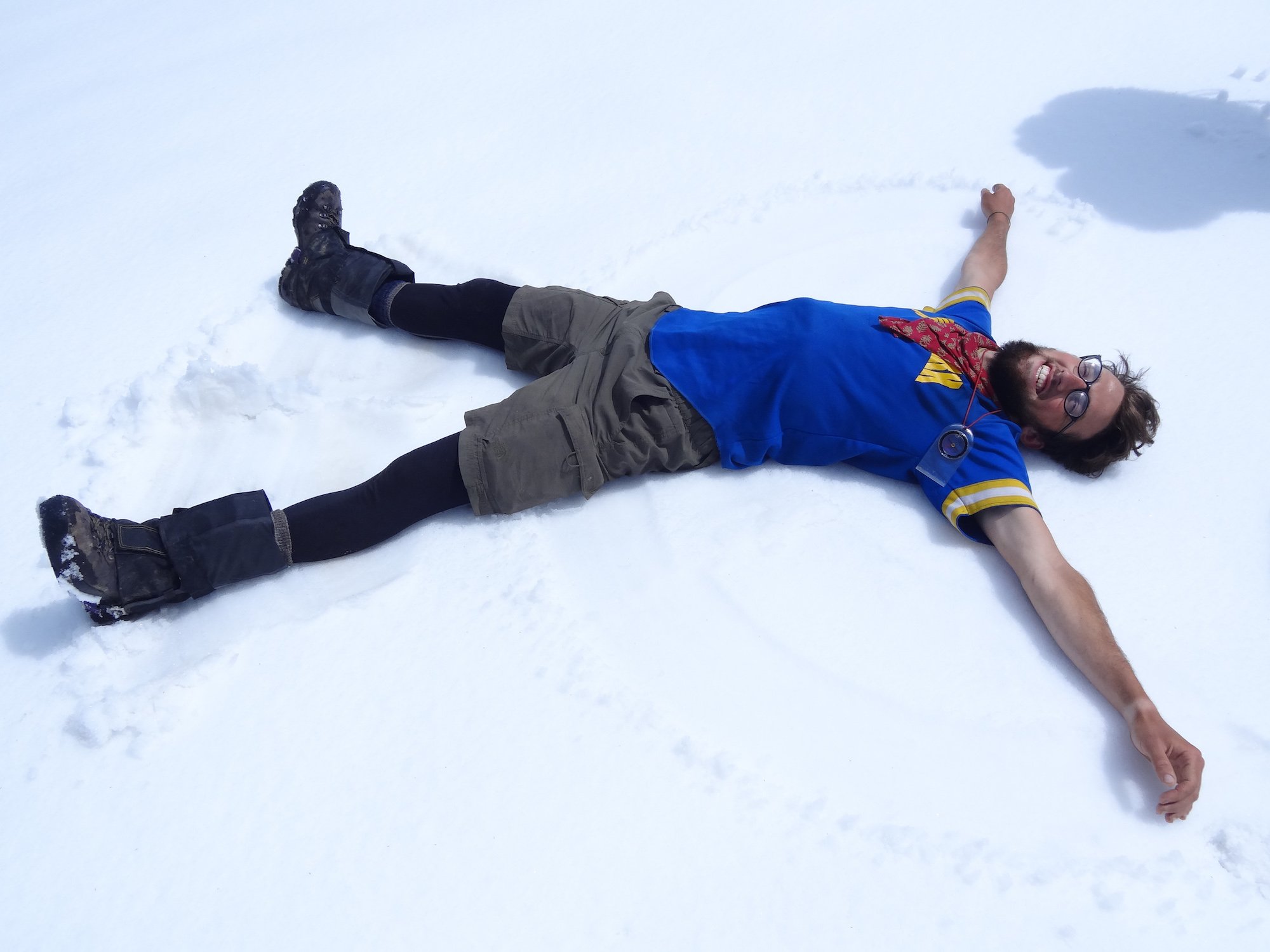 Smiling NOLS participant makes a snow angel