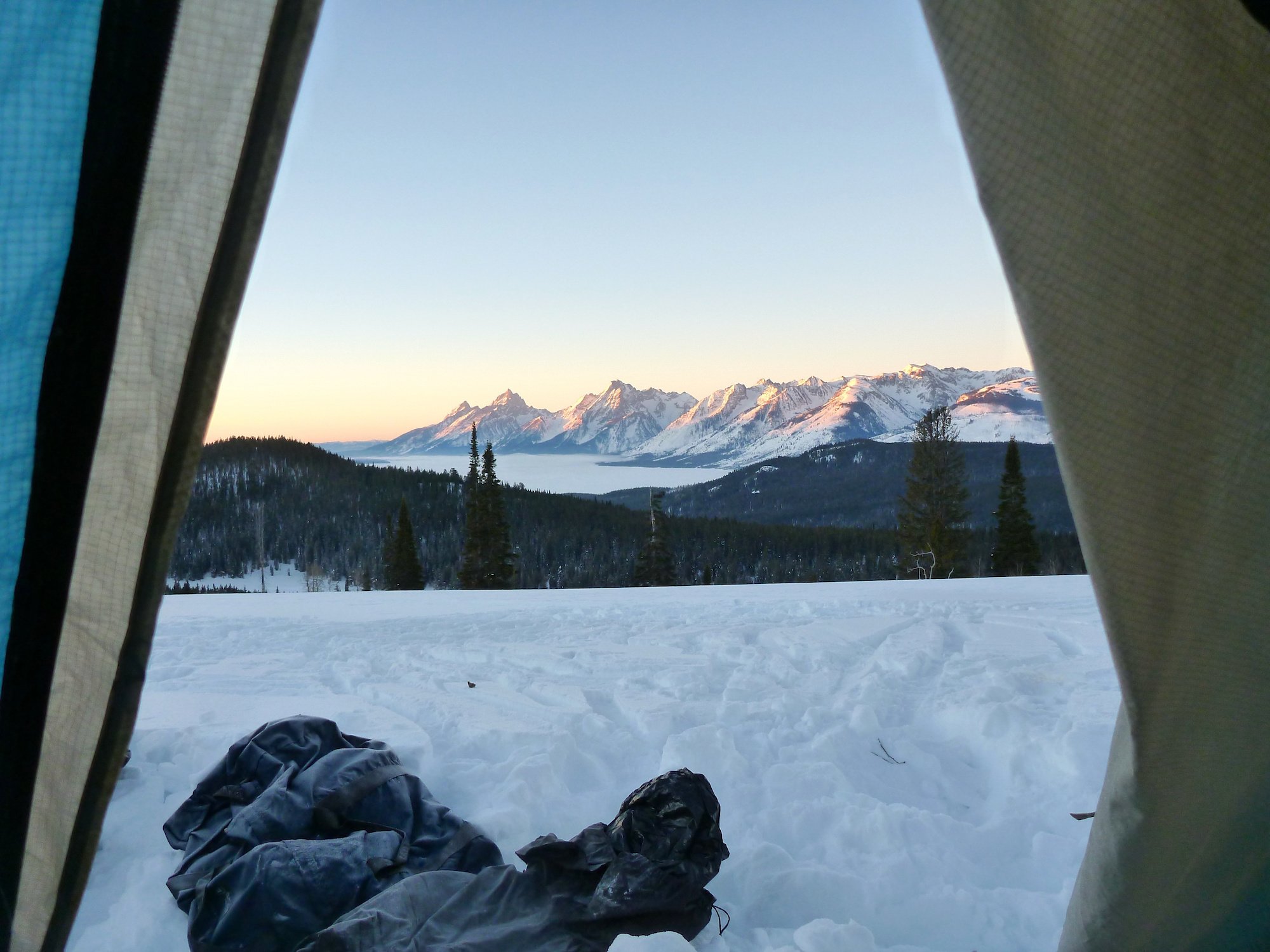 snow-covered mountain range at sunrise seen from a tent on a NOLS winter course