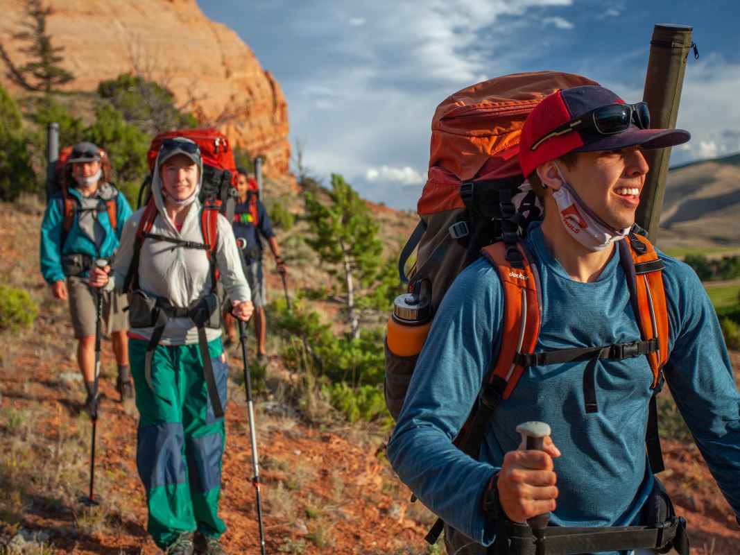 Group of backpackers with canyons in the background and cloth face coverings