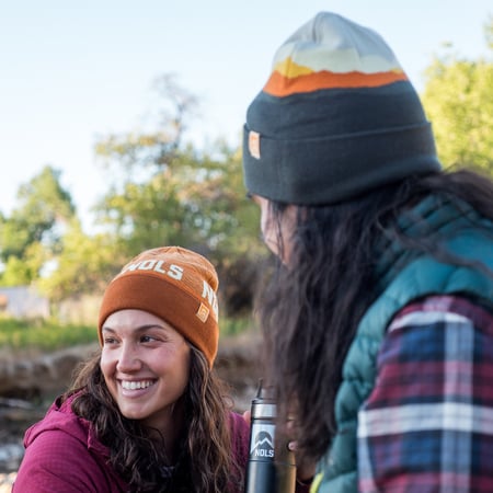 Two people wearing beanies smile