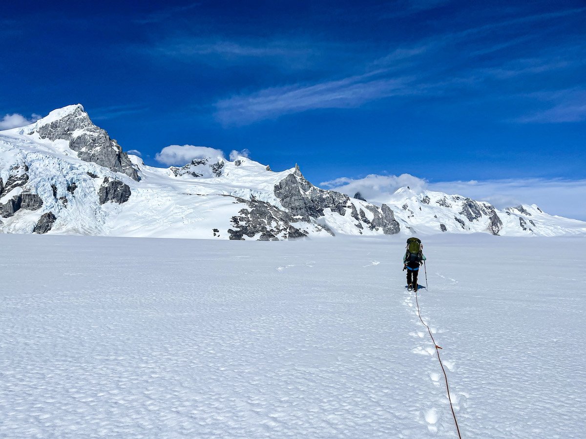 Woman crosses a large snow-covered glacier