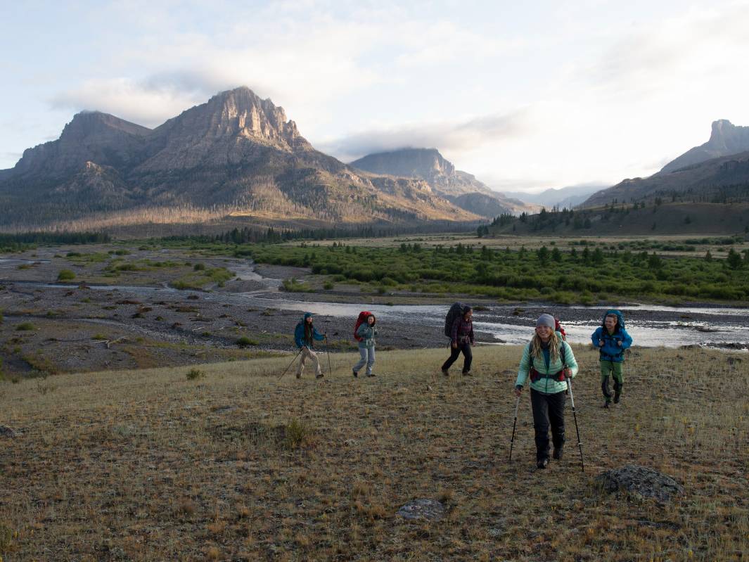 Hikers cross a mountain meadow