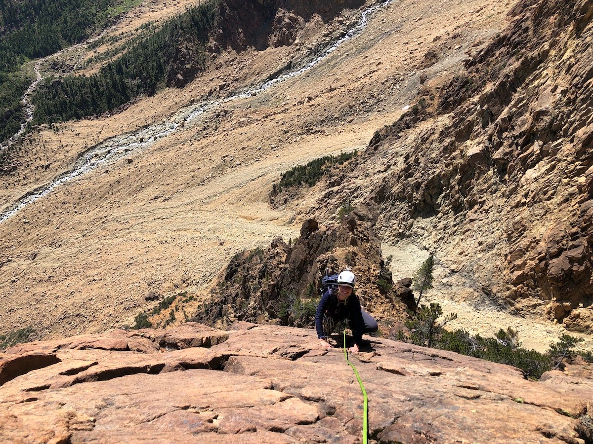 Climber ascends a rock face over a dry plain