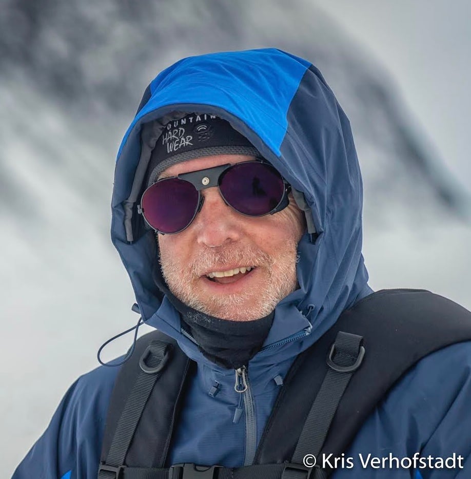 Close up of Eric wearing sunglasses and a hooded jacket for hiking