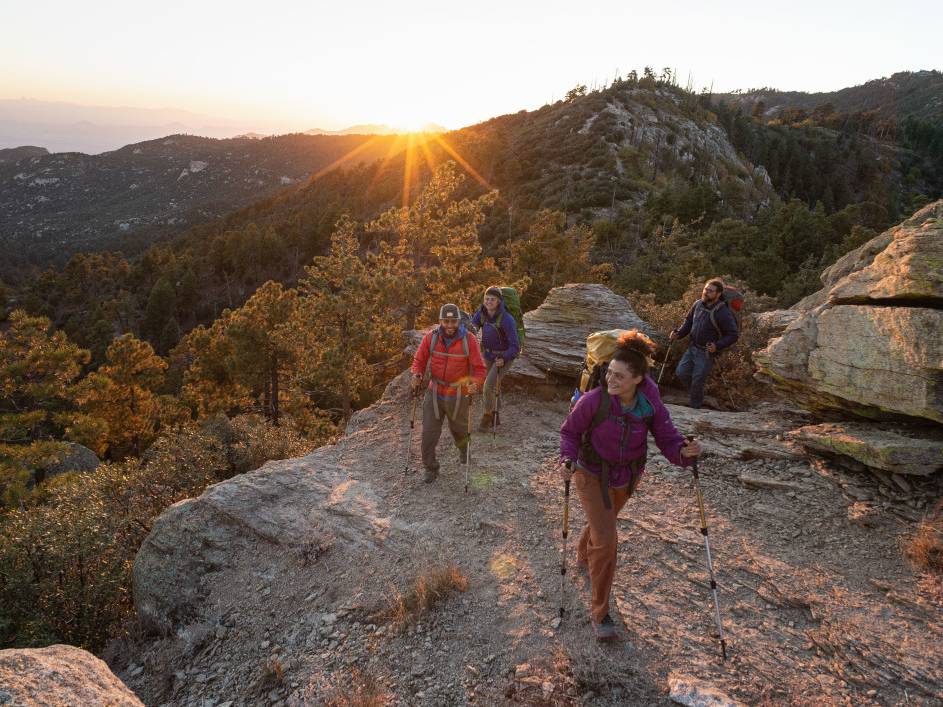 Three backpackers ascend a ridge