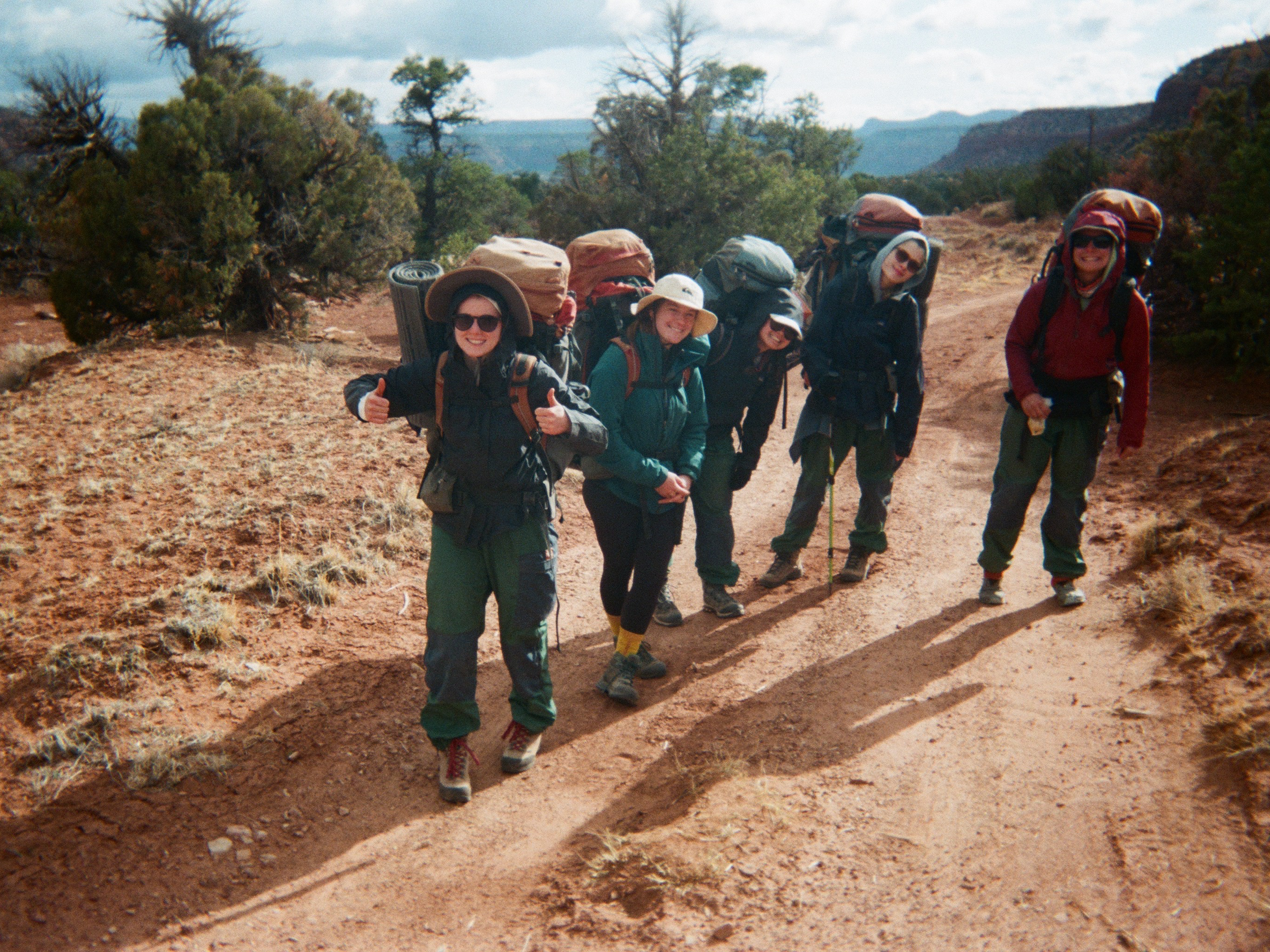 Group of five students smiling as the hit the trail for the day.