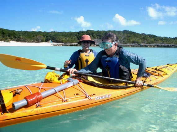 NOLS Alumni student in a kayak wearing goggles with an instructor standing by her.