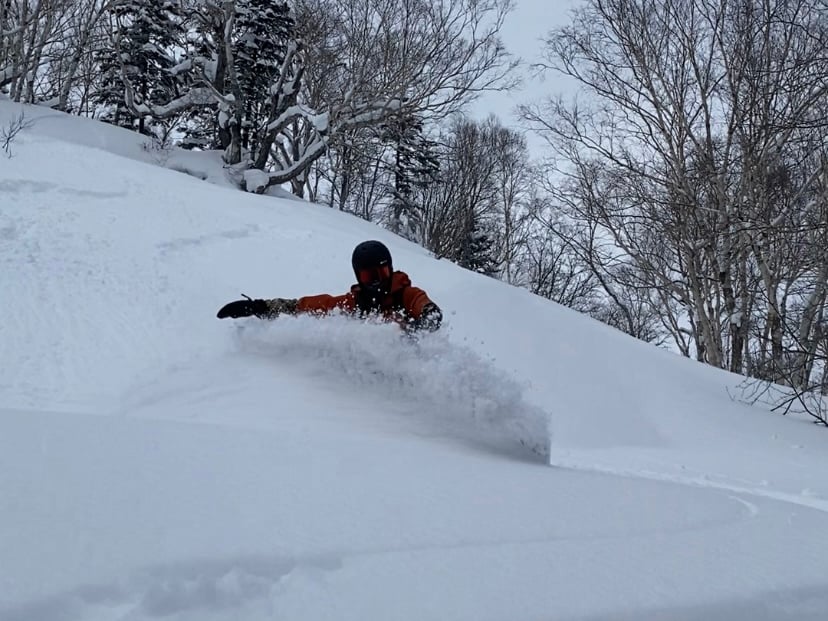 Skier in waist-deep powder coming towards the viewer