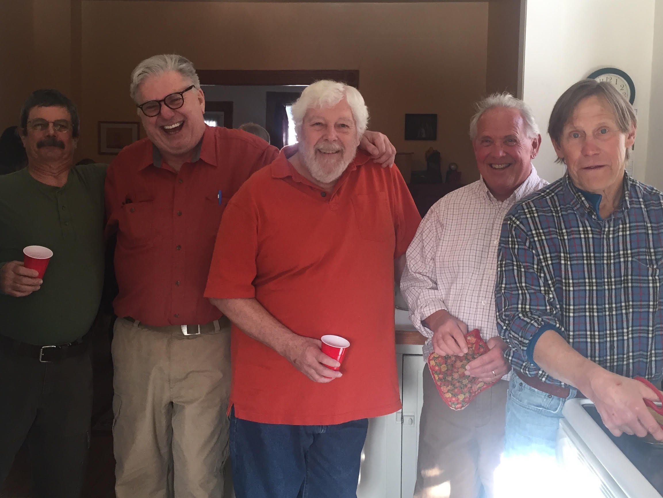 Peter Simer laughing with four friends in the kitchen at the home of Anne and Kevin McGowan