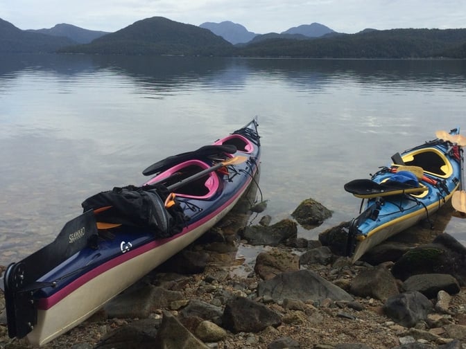 Two sea kayaks beached on a rocky shore