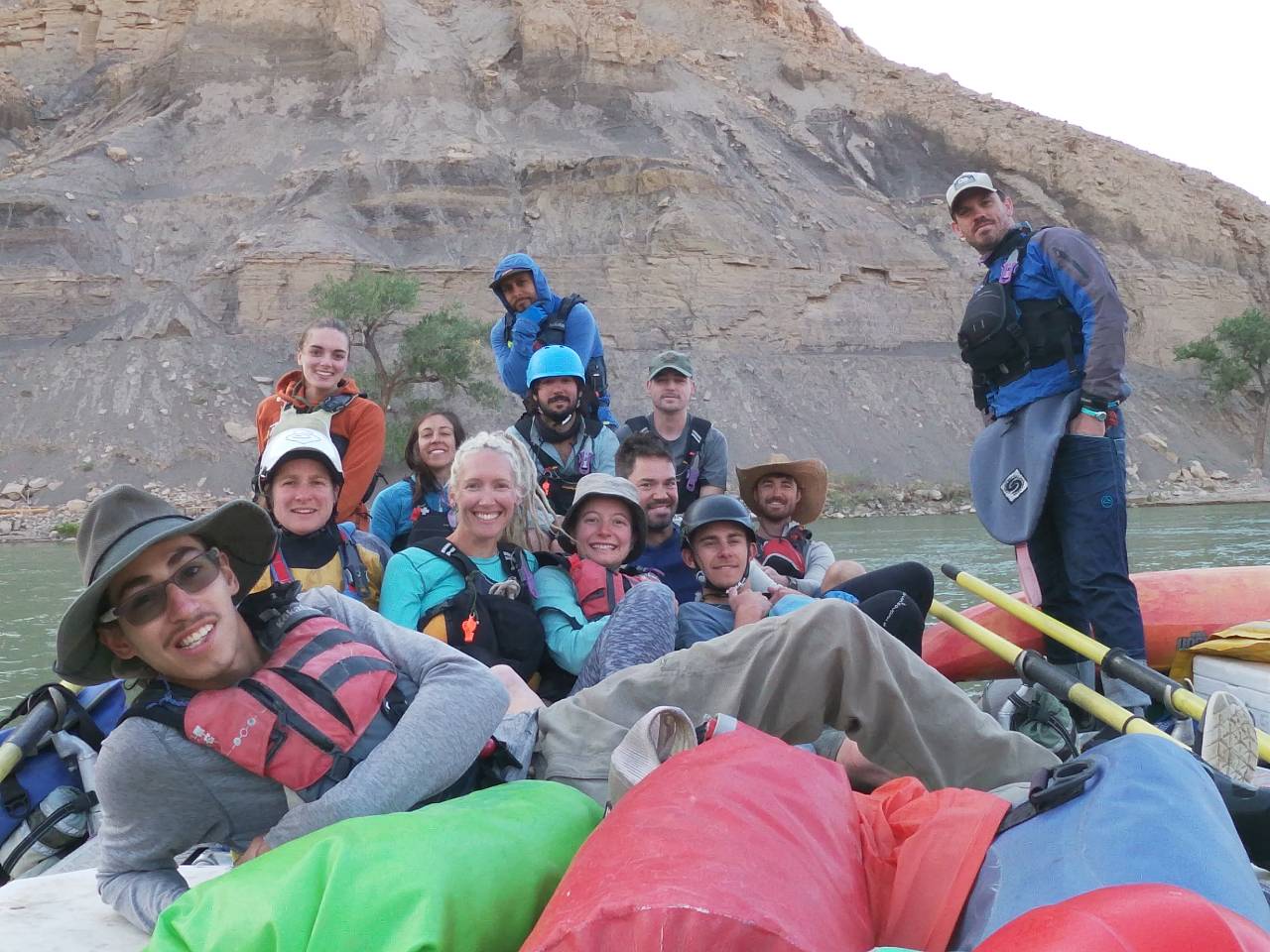 NOLS group smiles while resting on a river bank