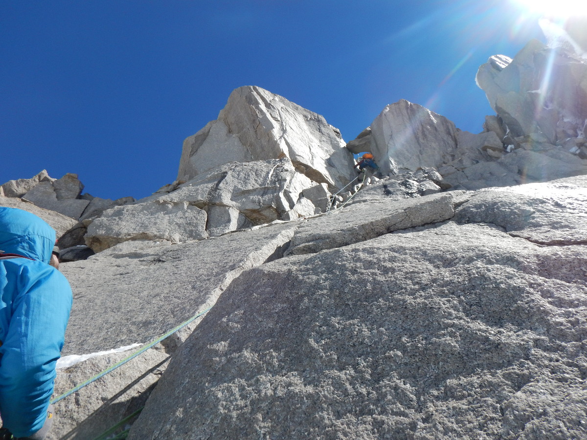 one climber belays another while climbing a steep rock face in Patagonia