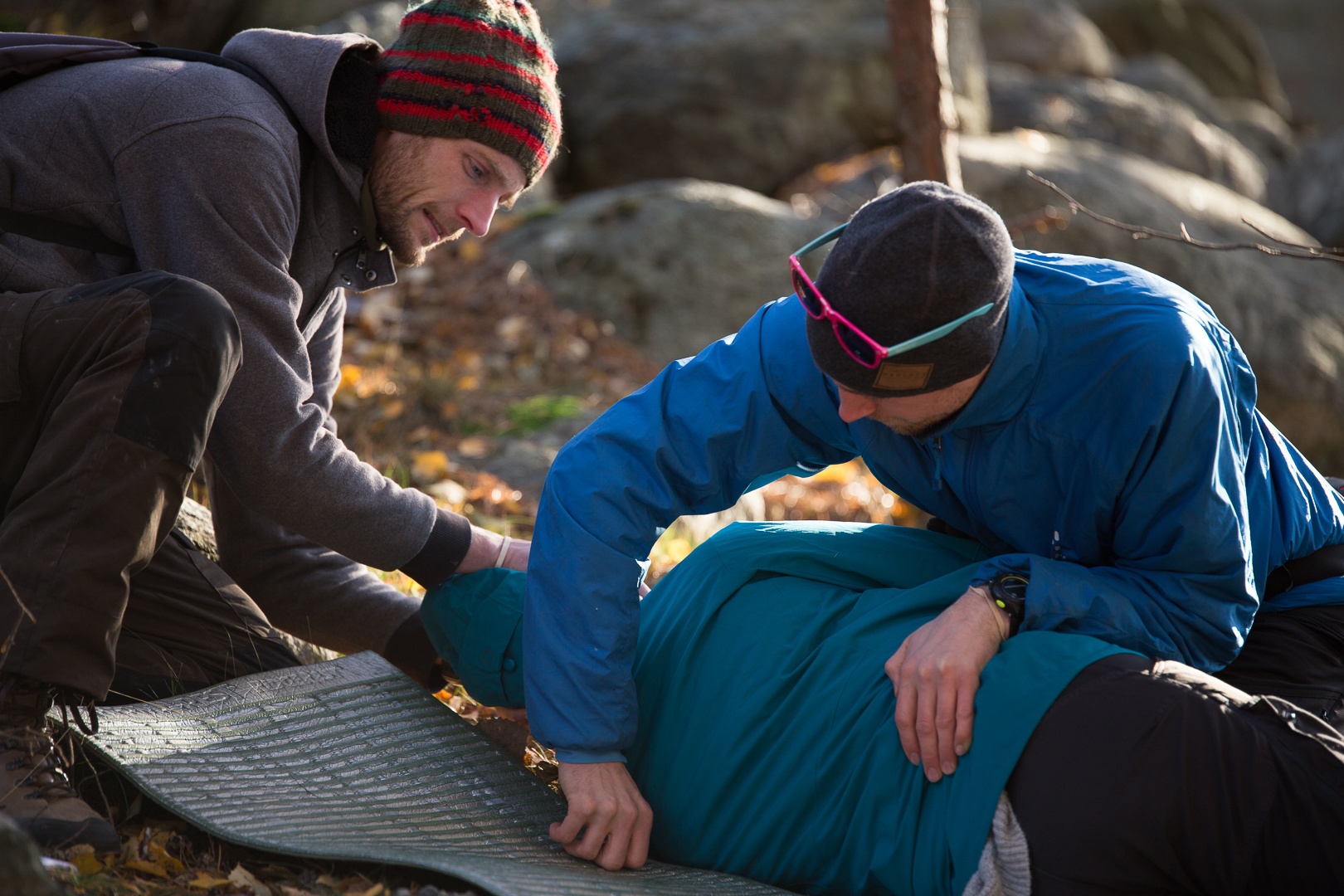 Two wilderness medicine students practice rolling a patient onto a foam pad