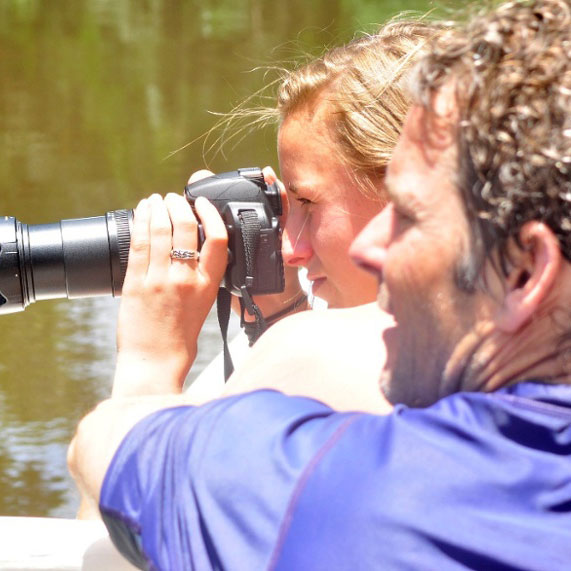 Father and daughter use a camera outdoors togethe