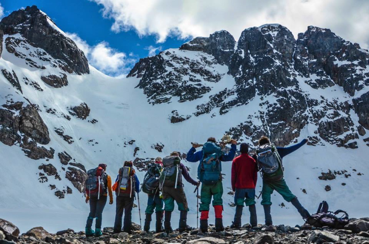 The backs of seven students facing a mountain peak