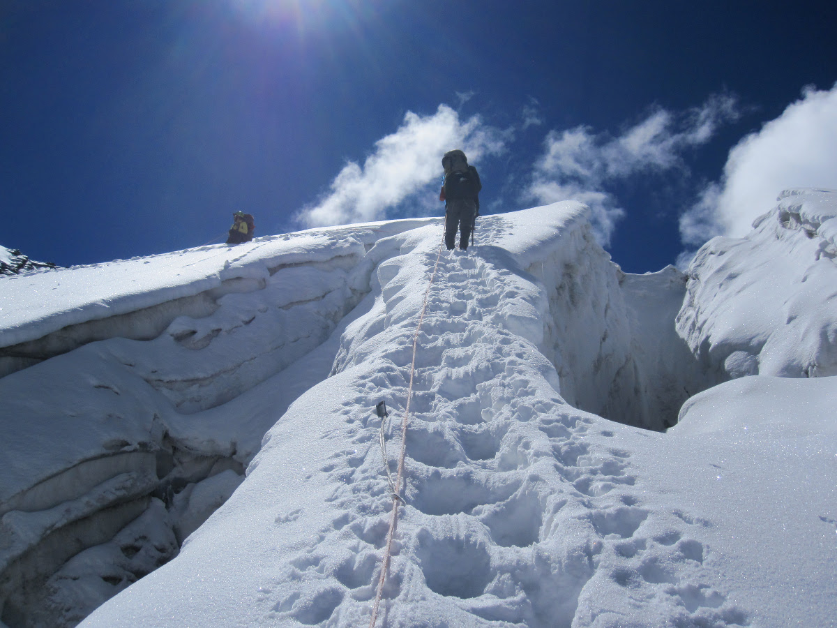 Looking up at a person climbing up snow steps kicked into the glacier