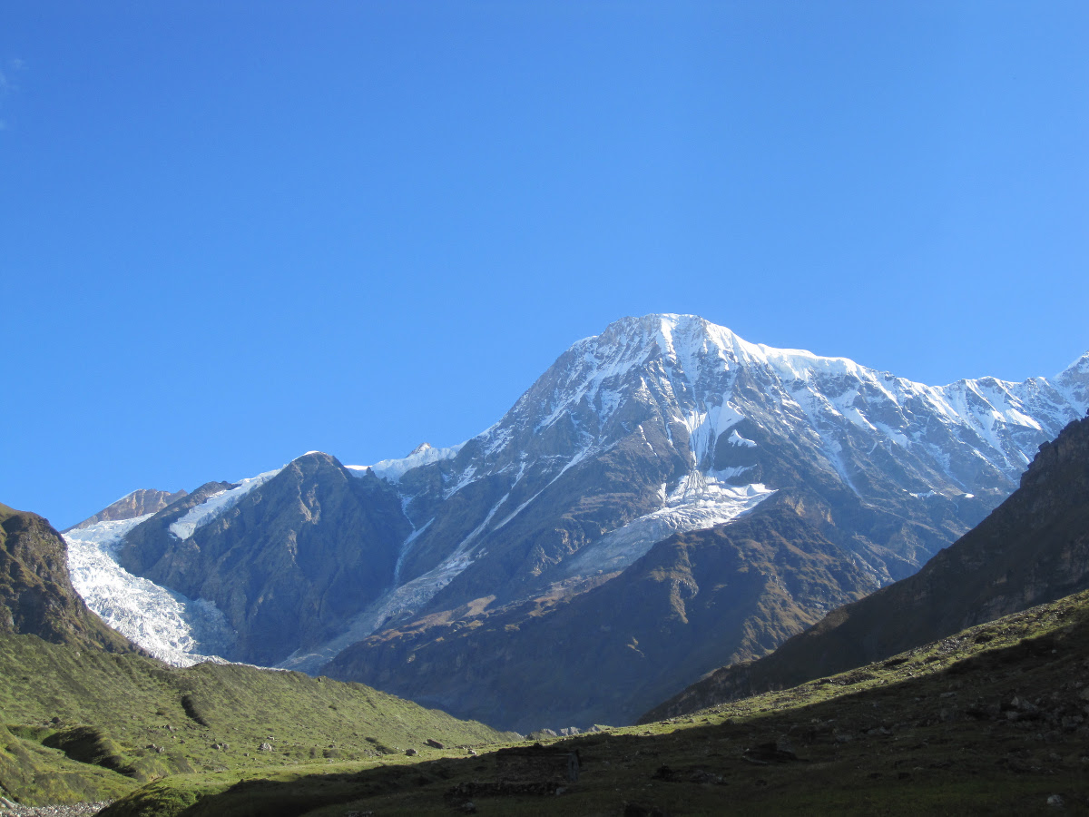 green valley rising to huge snow-covered peaks on a sunny day in the Himalayas