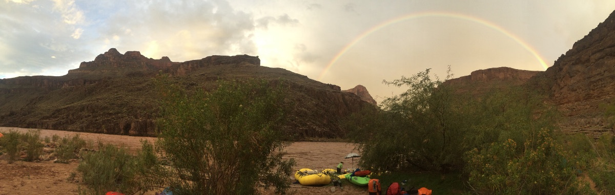 Full rainbow arcs over the canyon at a river camp