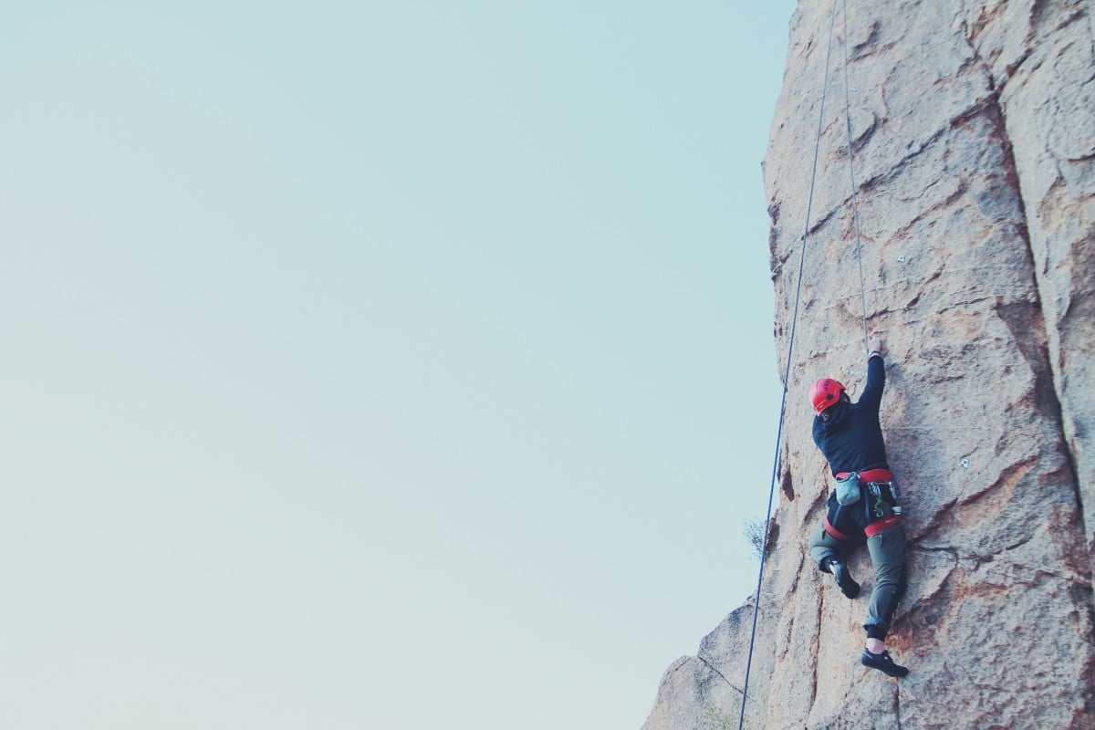 rock climber wearing red helmet moves up a pitch at Cochise Stronghold