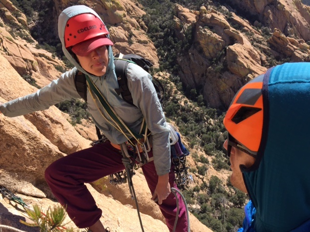 two NOLS instructors pause to talk while climbing on reddish rock in Cochise Stronghold