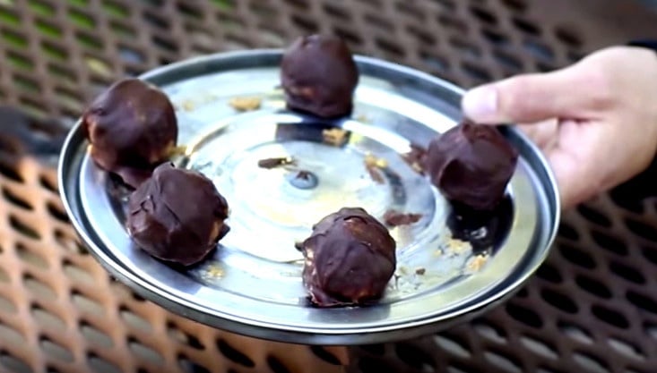 hand holds five peanut butter truffles on a tin lid