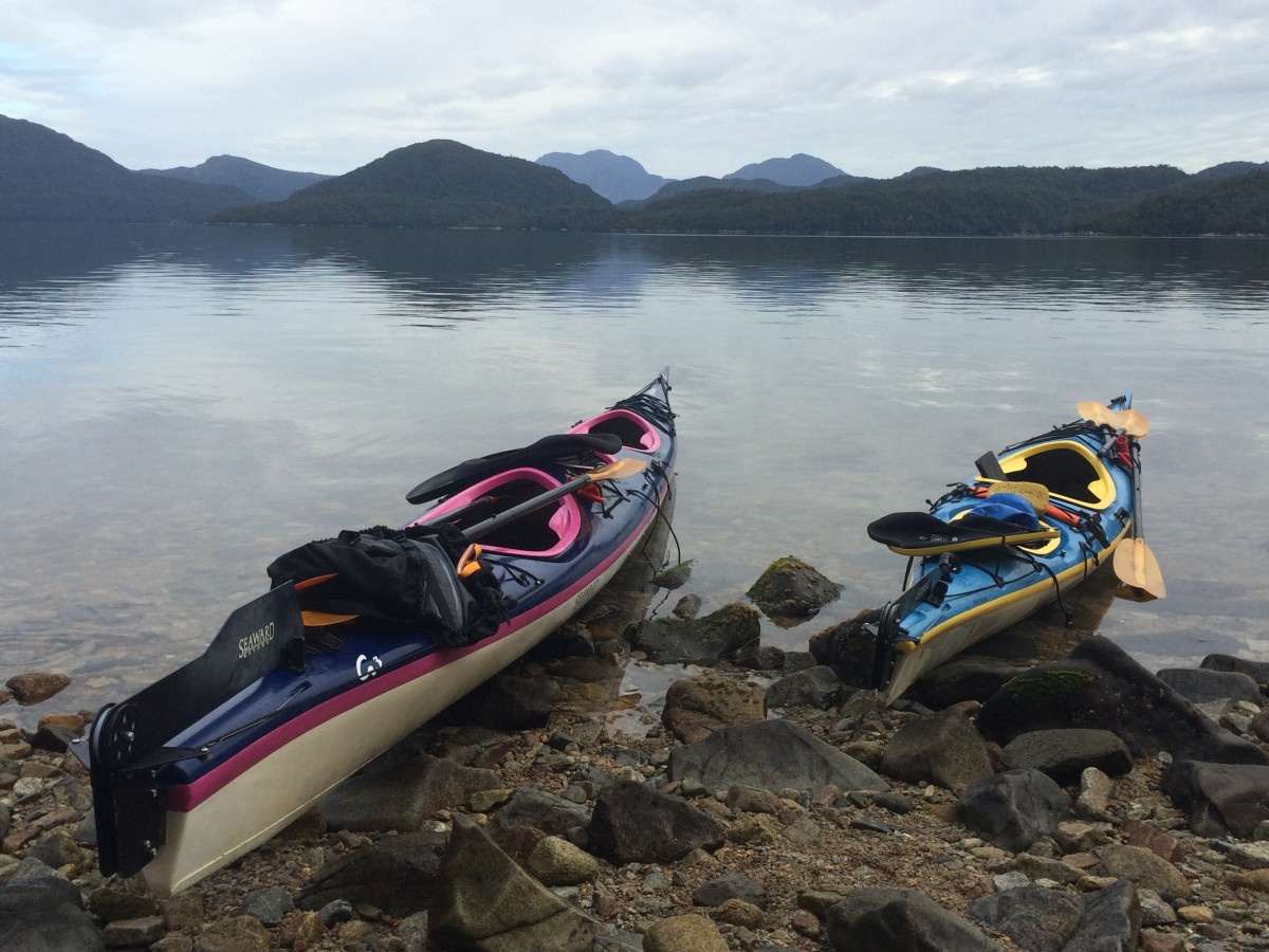 Sea kayaks resting on a mossy rock