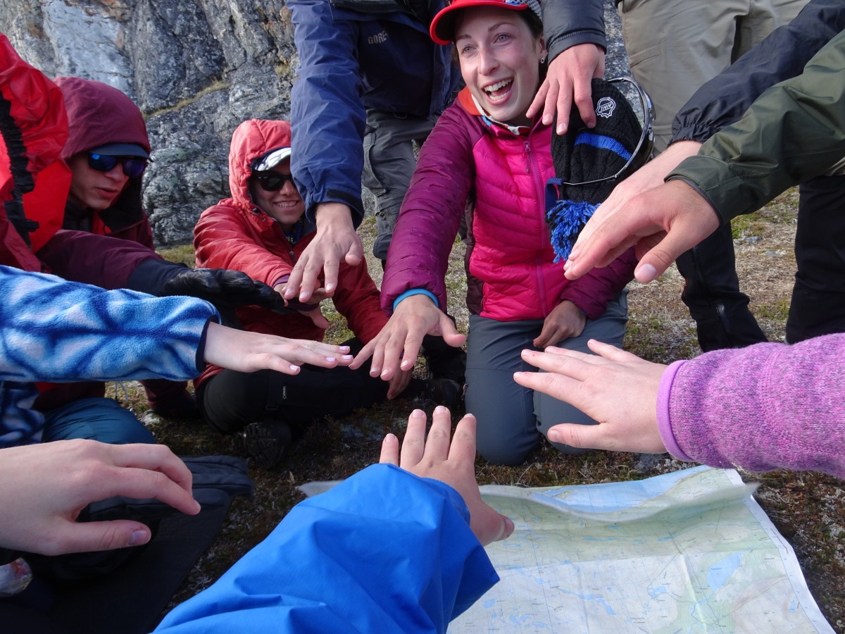 Happy group puts hands in the middle on top of a map