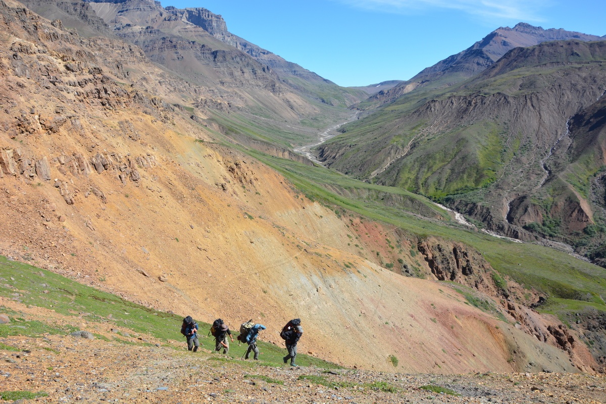 four students hike across steep terrain in Alaska's mountains