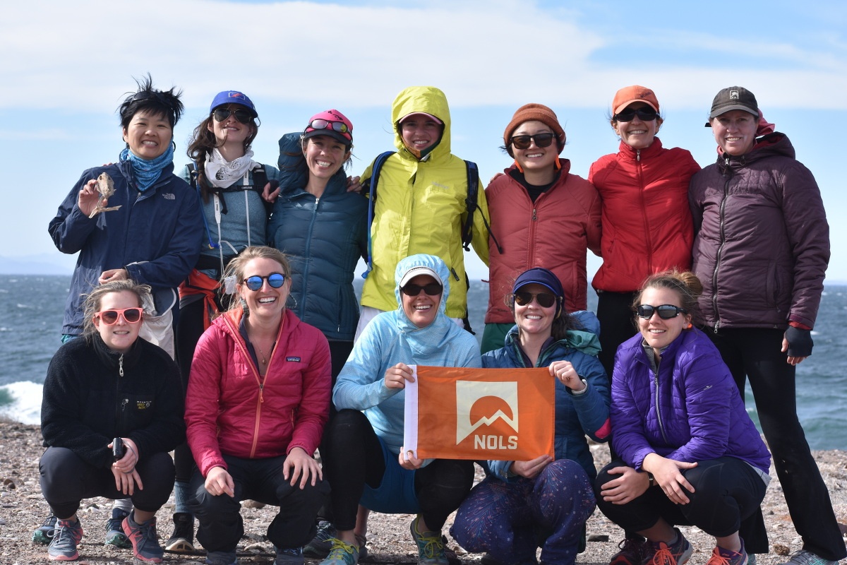 The entire group together smiling and holding a NOLS flag