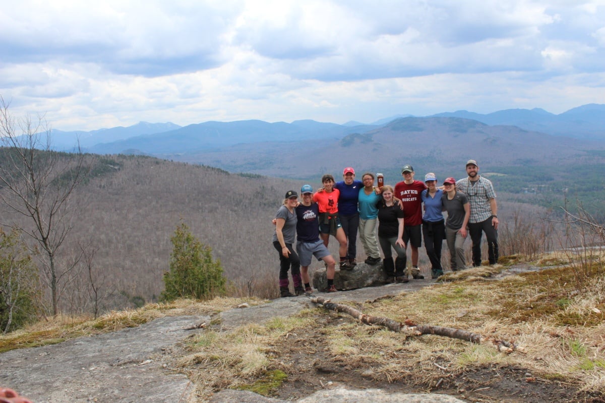 Bates College students smile and stand together for a group shot in the Adirondack mountains