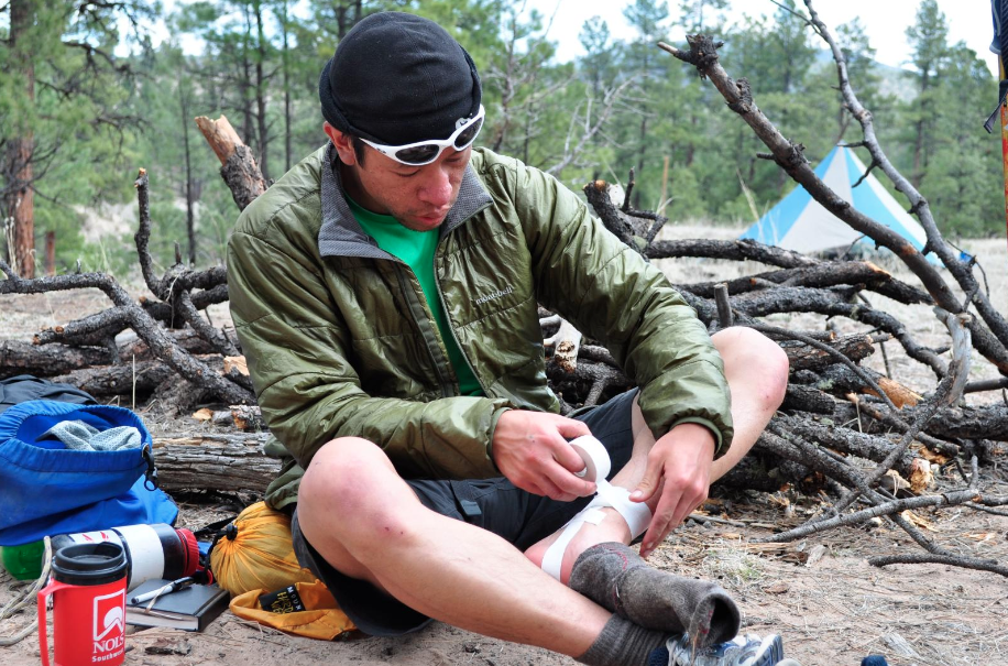 Man sitting in camp and taping his ankle