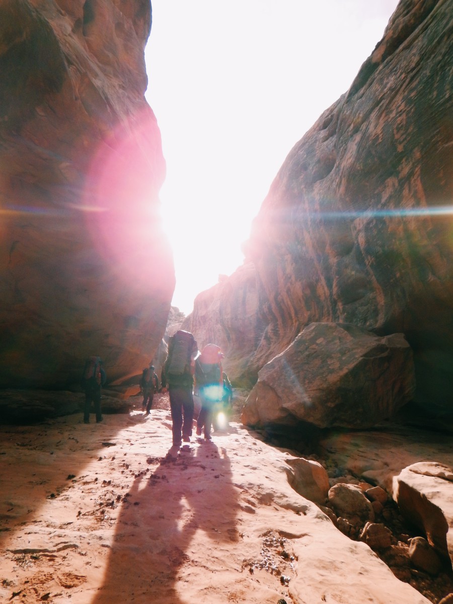 Figures walk away from camera into the sun in the canyonlands