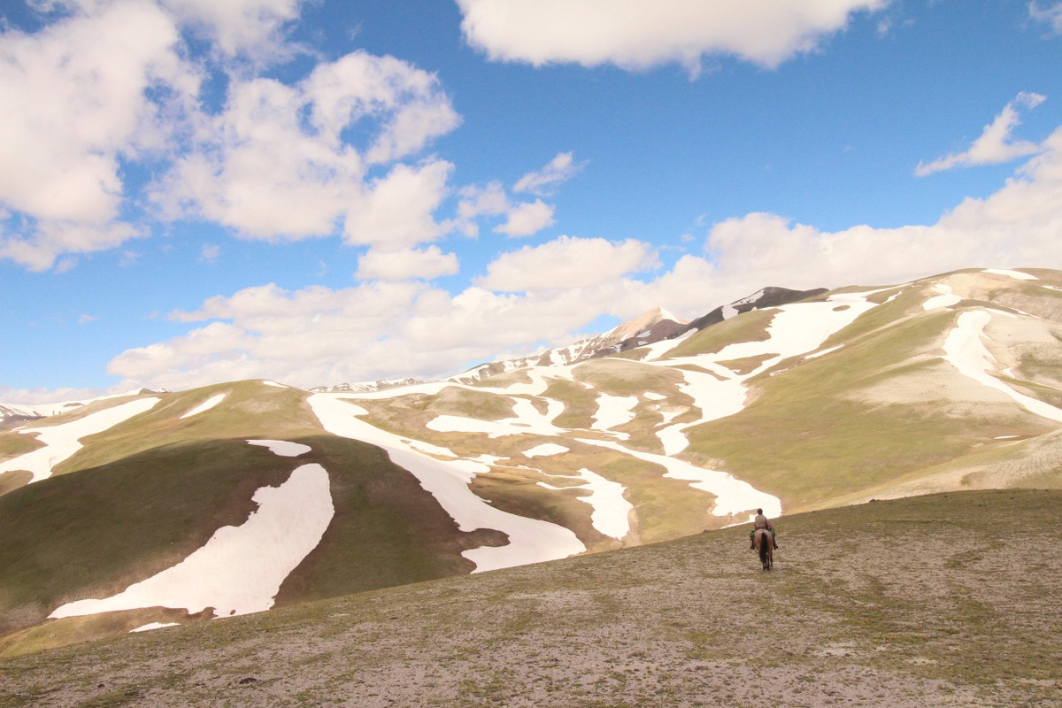 Single horsepacker with snow-striped mountains in the background