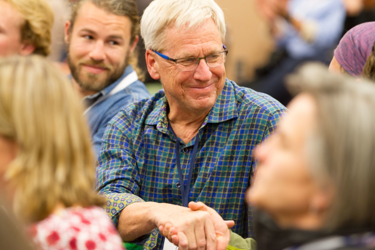 long-time NOLS President John Gans smiles and shakes someone's hand