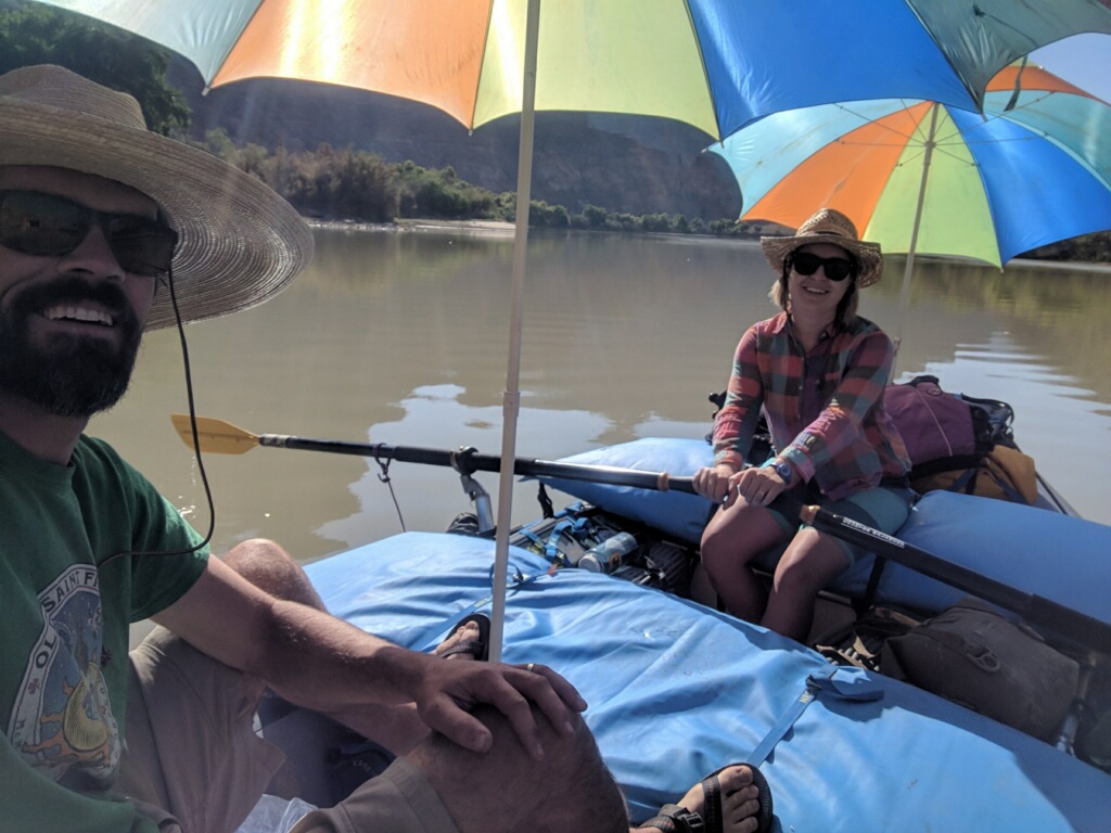 Ashley and Kyle paddling with sun umbrellas on the boat