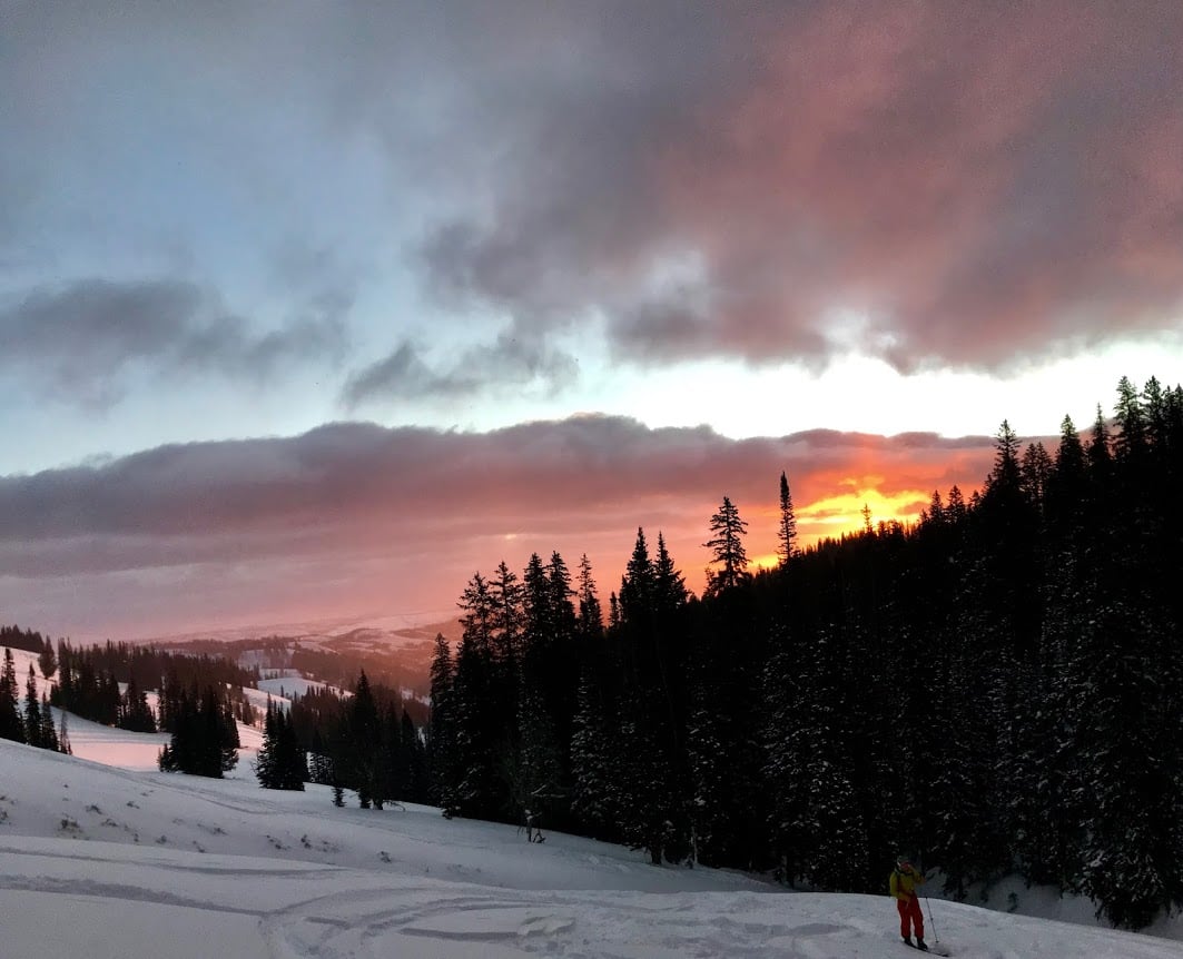 NOLS student backcountry skiing with sunrise in the backdrop