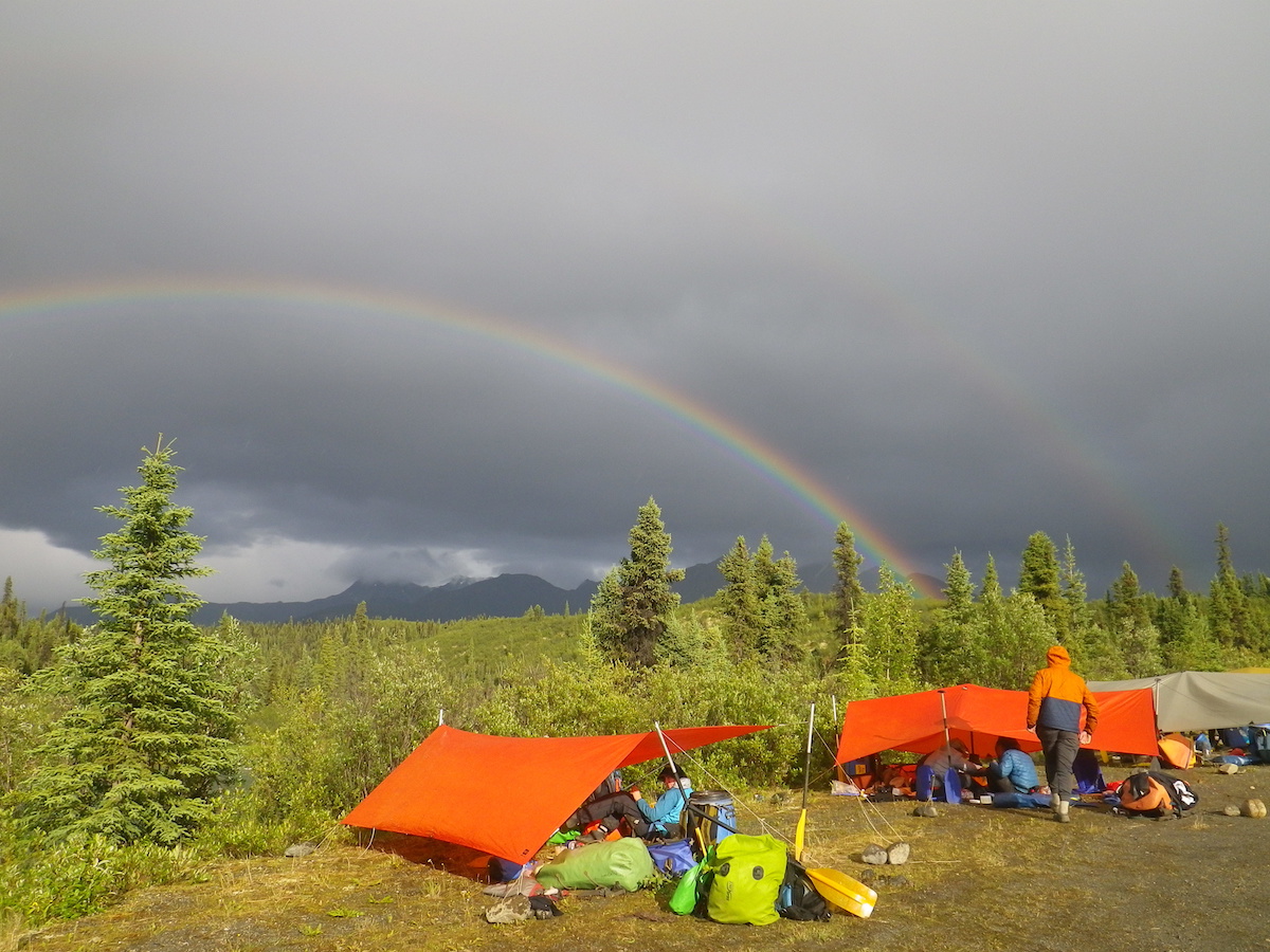 double rainbow above a campsite in the Yukon with two orange tarps set up