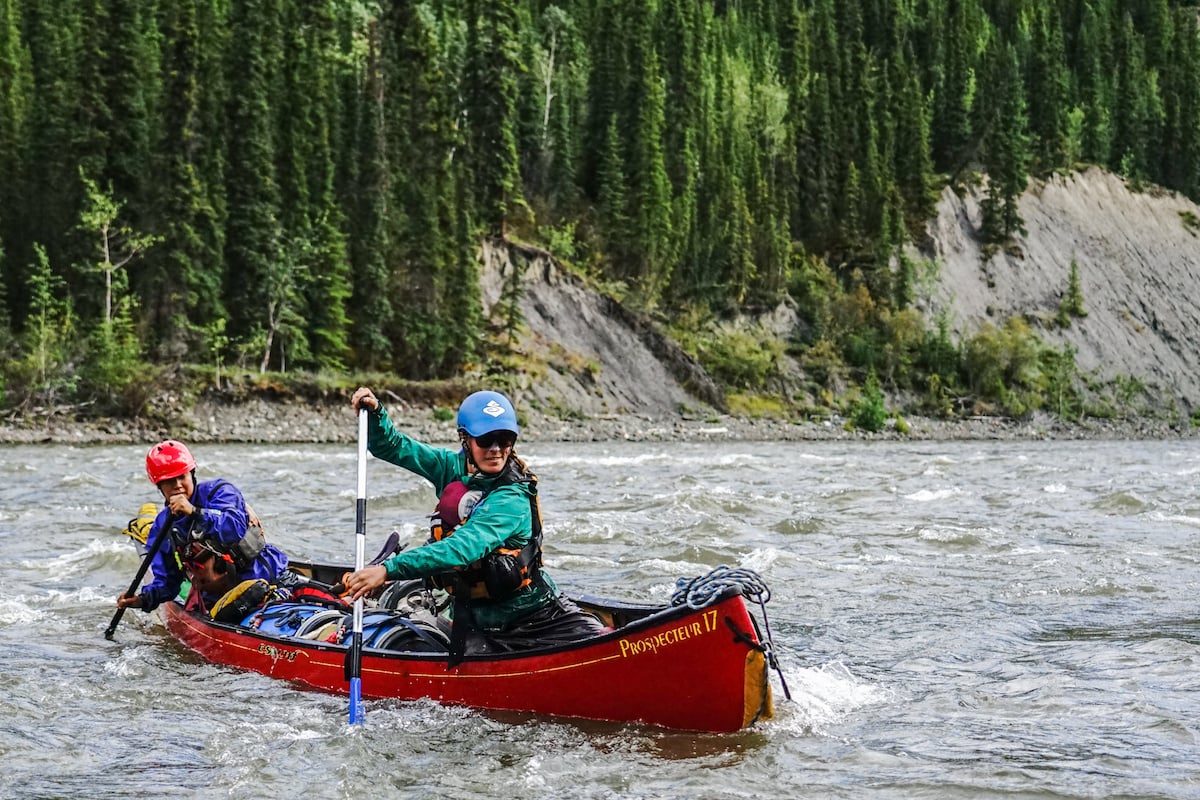 two NOLS students paddle a whitewater canoe on a river in the Yukon