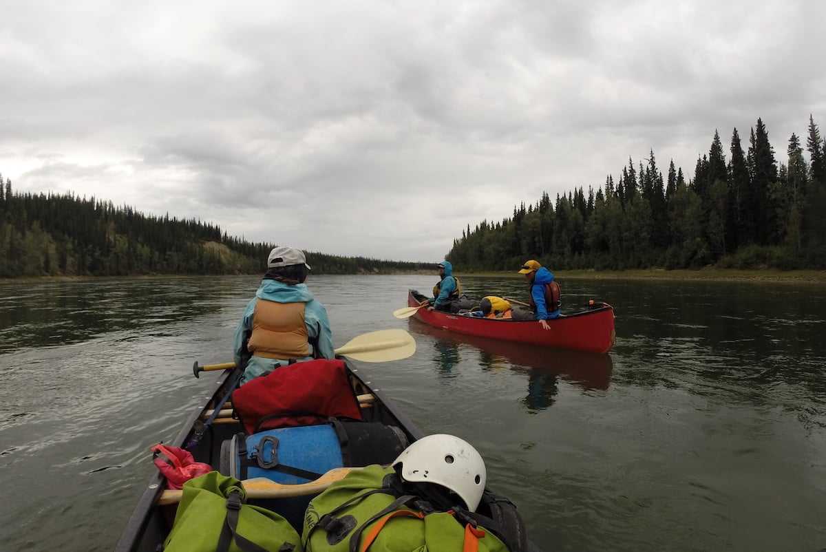 NOLS students paddle canoes in the Yukon on a cloudy day in calm water