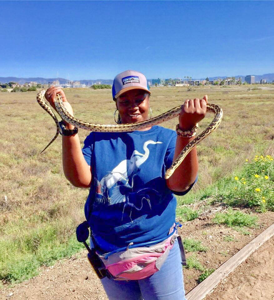 Day Scott smiles while holding a gopher snake as she leads a nature walk in a California wetland