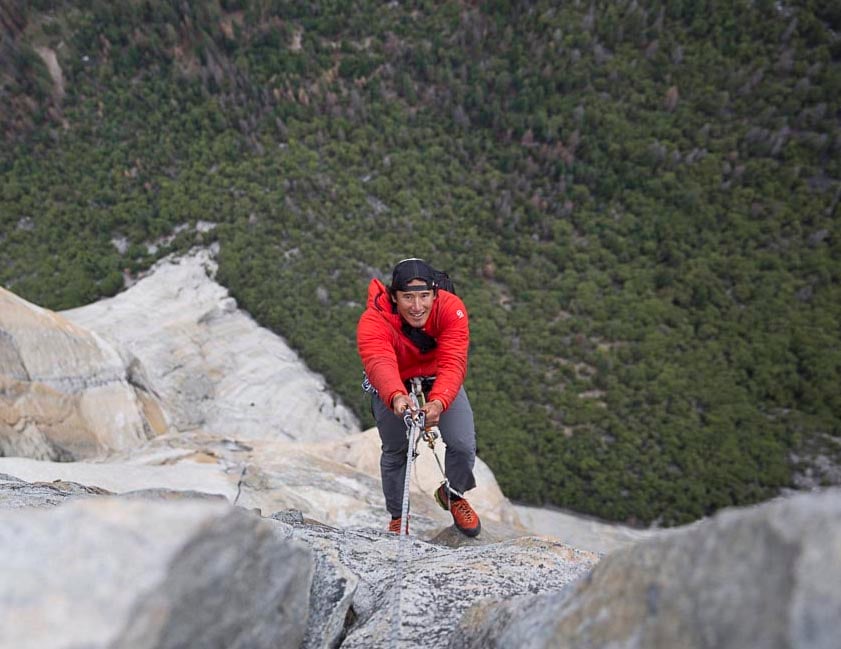 smiling Jimmy Chin rock climbing, as seen from above