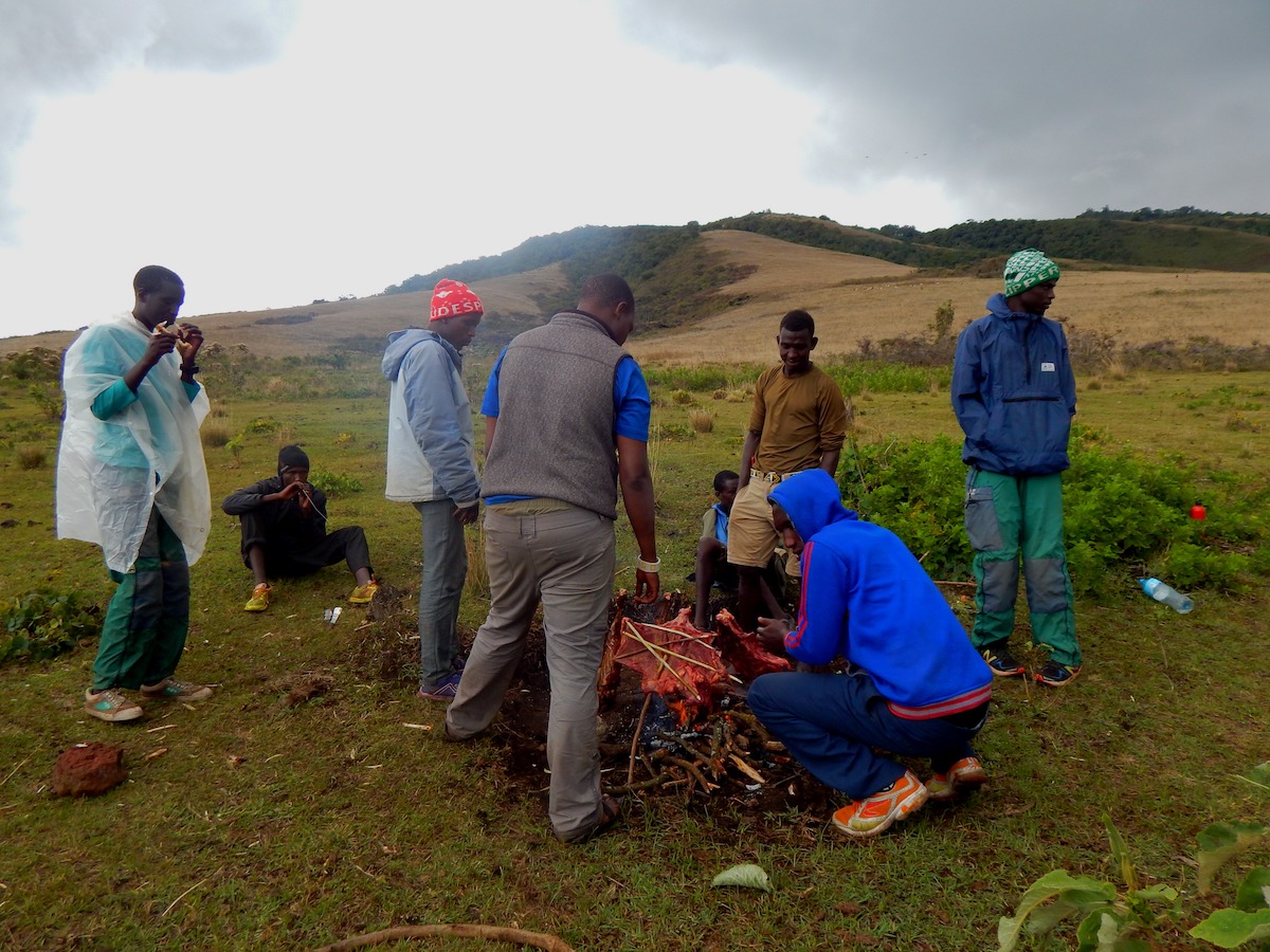 Maasai men show NOLS participants how to roast a goat in the traditional manner