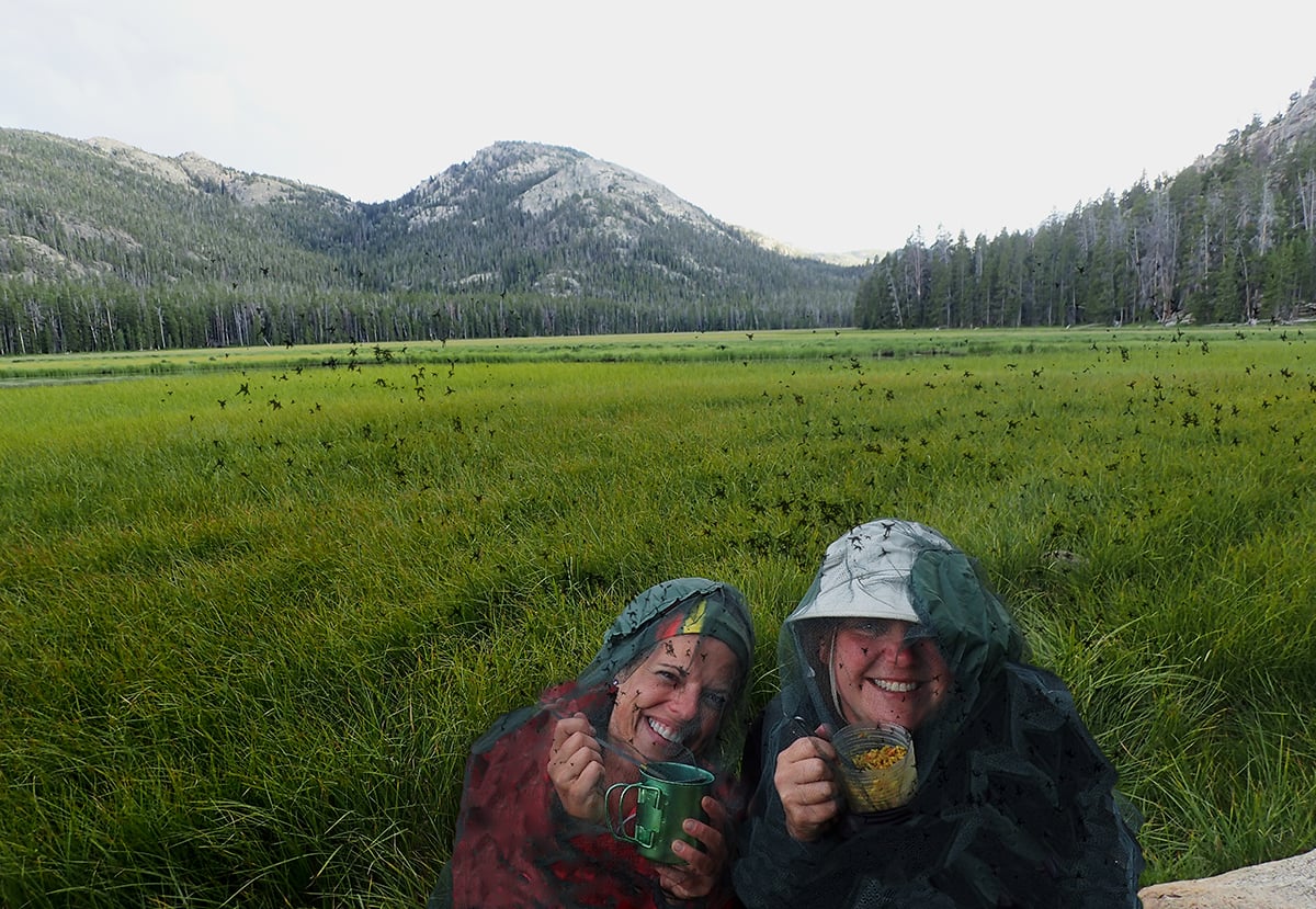 People eating while wearing full-body bug nets