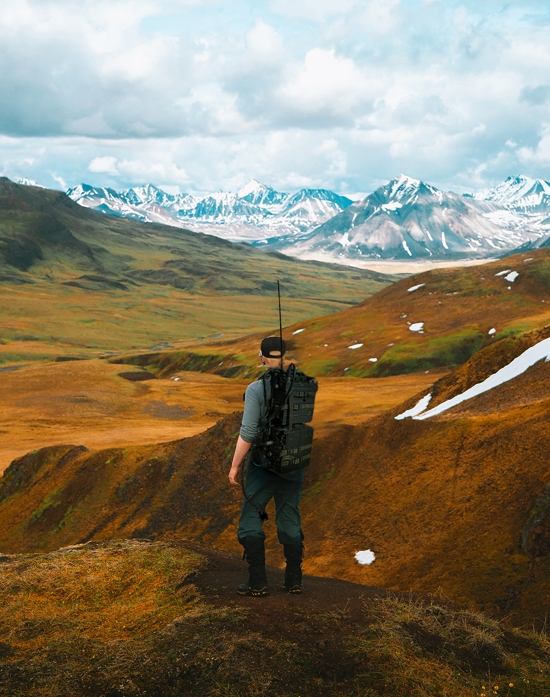 Person wearing large heavy backpack with mountain background